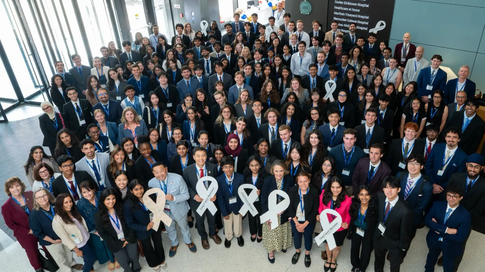 A large group photo of 2026 ALCSI Summit attendees holding white ribbons