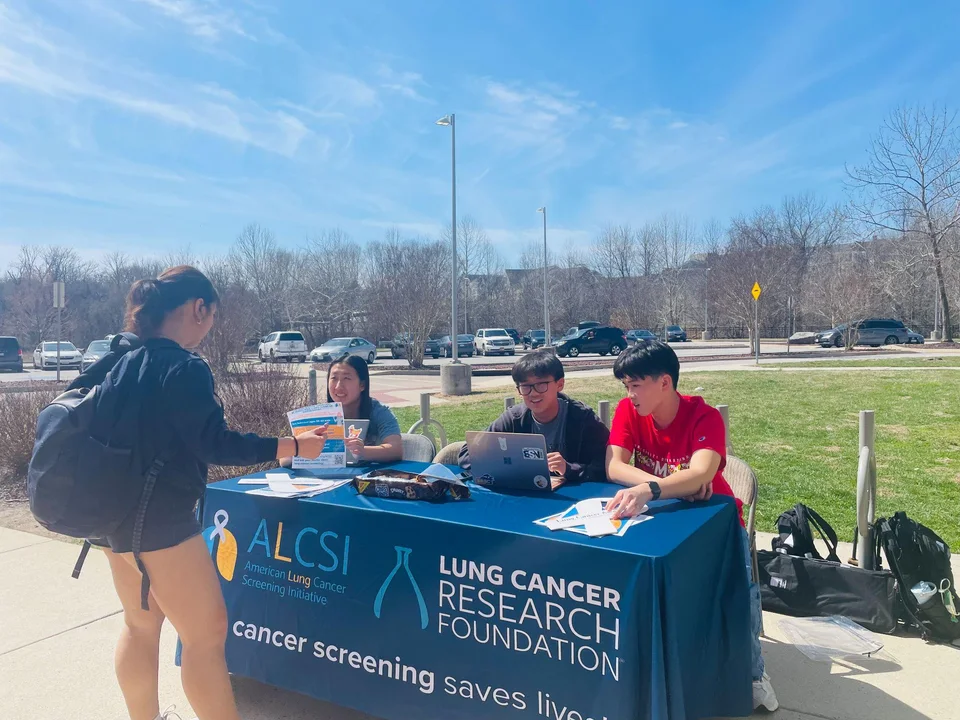 Students speaking with a passerby at an ALCSI table outside Miller Branch Library