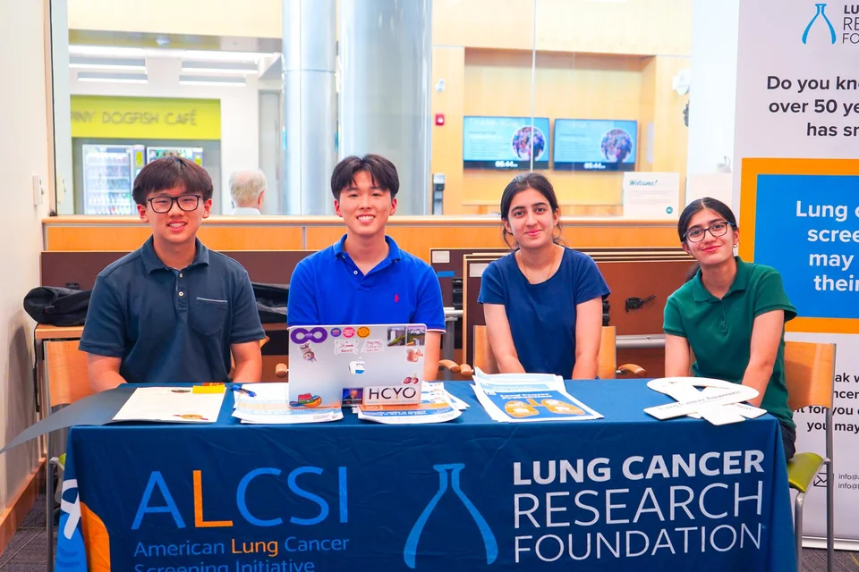 Four student volunteers seated at an ALCSI table